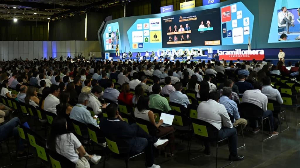 Auditorio repleto en el congreso CAMACOL 2019 producido por Herman Piza: cientos de asistentes frente al escenario con pantallas de patrocinadores y panel de conferencistas.