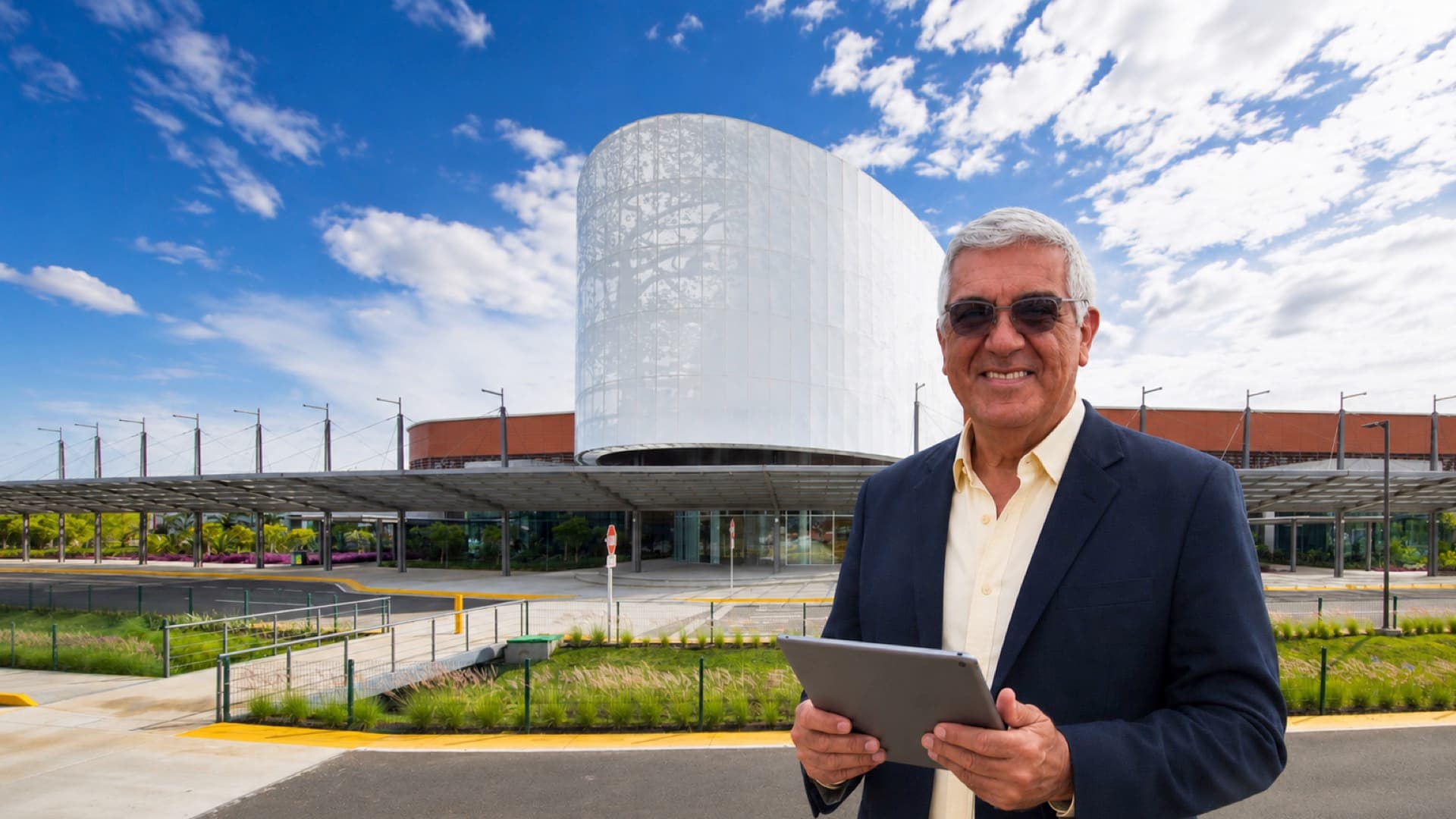 Herman Piza con una tablet frente al centro de convenciones donde opera la tecnología de sus eventos.